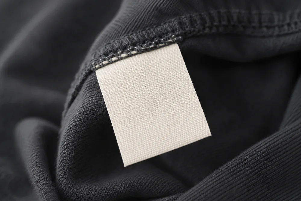 A blank woven care tag inside a garment seam, photographed close up.