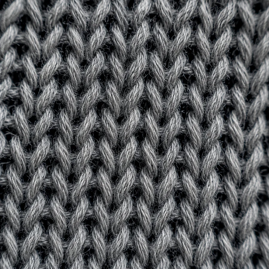 Macro photograph of a knitted fabric imitating denim, showing interlocking loops.
